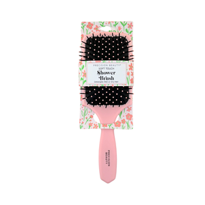 Pink hairbrush with black bristles in packaging on a white background